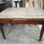 Early 1900s wooden table with pull-out extensions.